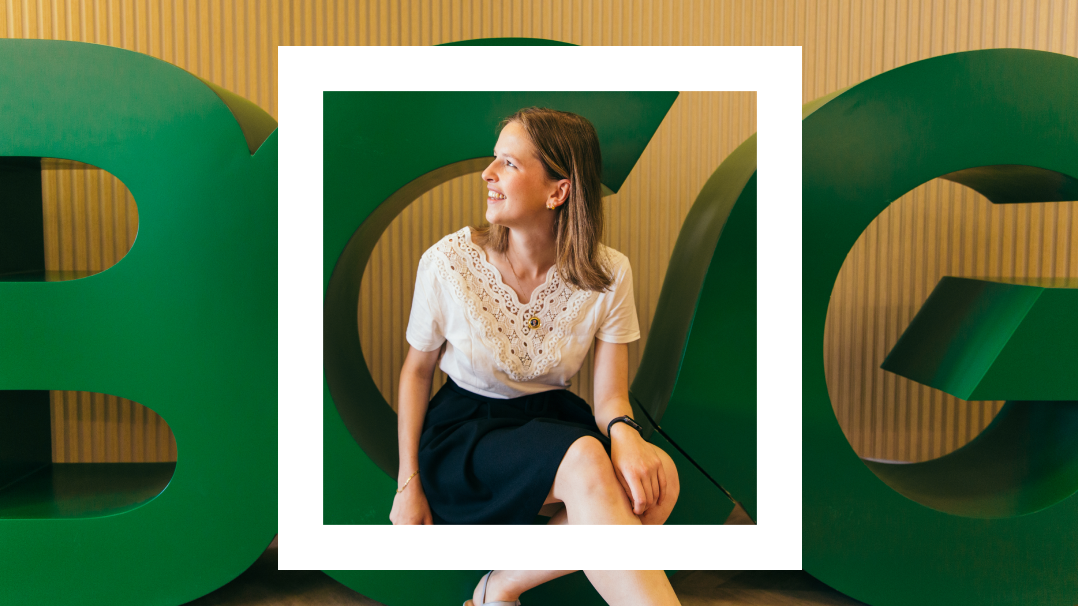 This image features a young woman seated in front of large, oversized green letters 