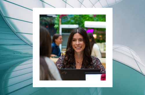 A smiling woman working on a laptop at an outdoor cafe, framed against an abstract architectural backdrop.
