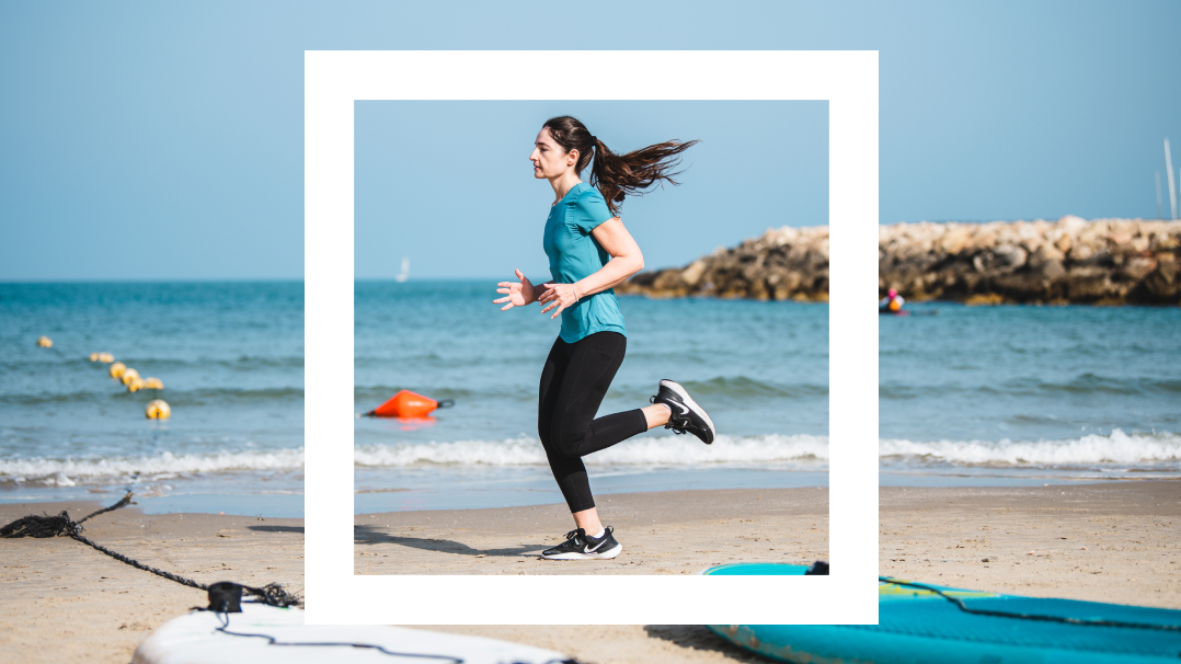 A woman is dressed in athletic clothing jogging on a beach with the ocean behind her. She is framed by a white square.