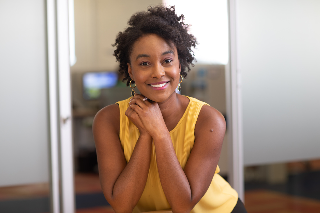 Person seated in an office space with hands resting under chin.