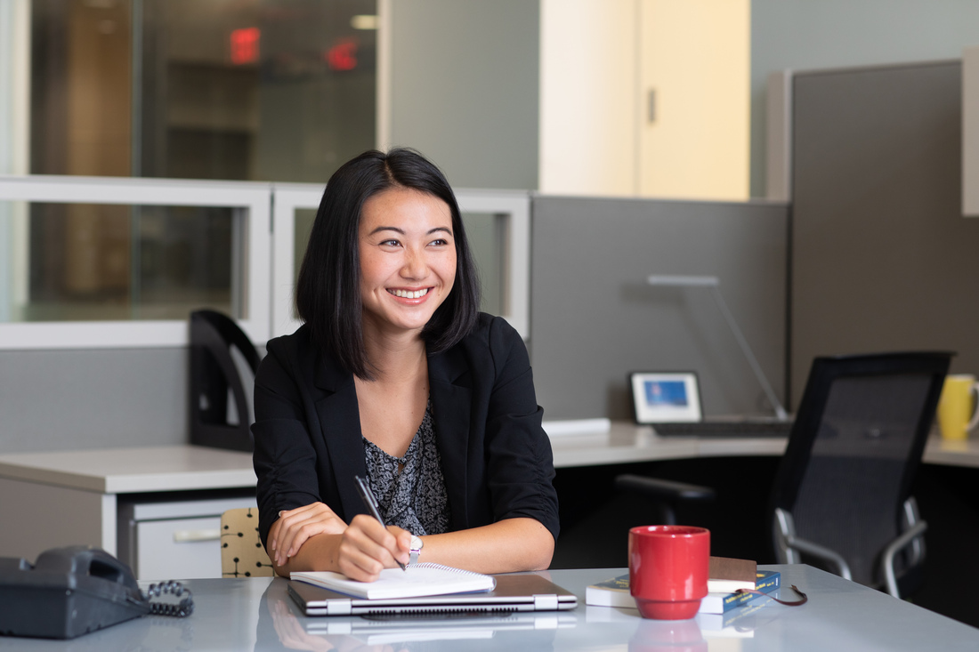 Person writing in a notebook at an office desk.