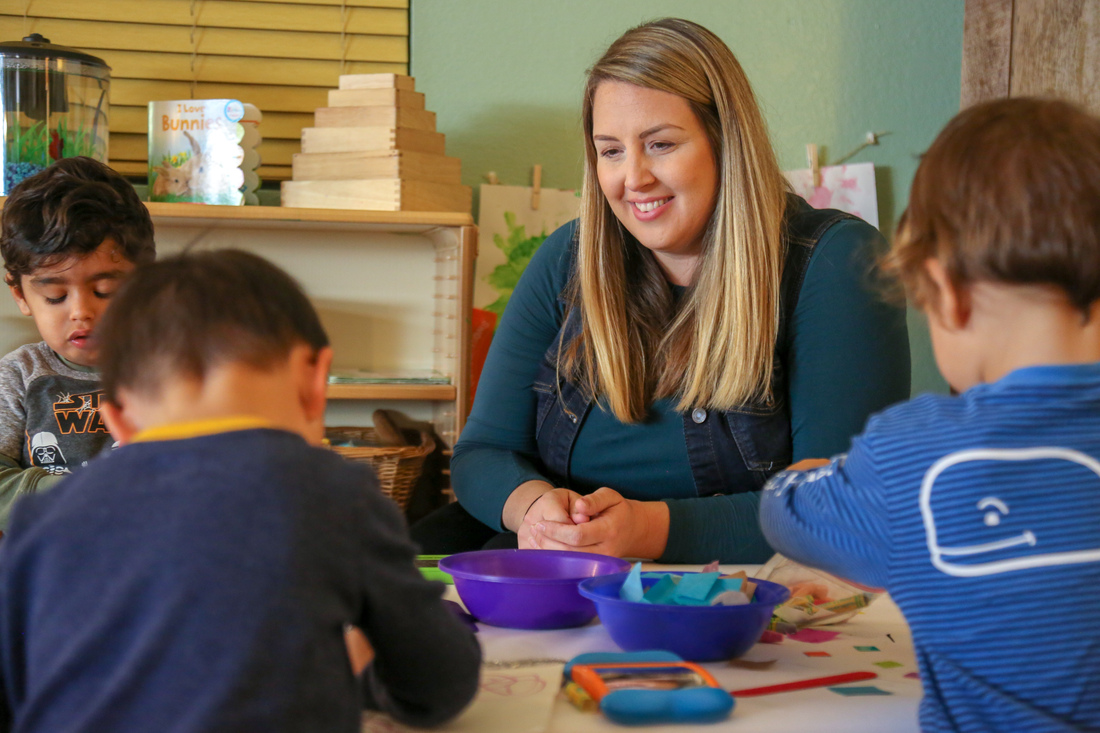 Adult and children working on an art project at a table.