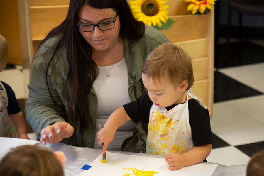 Child finger painting with yellow paint during an art activity.