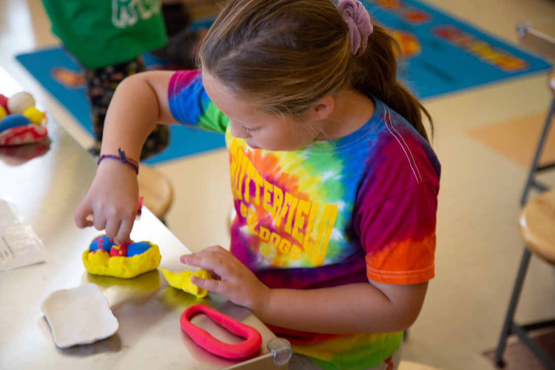 Summer camp student shaping colorful playdough during an art activity.