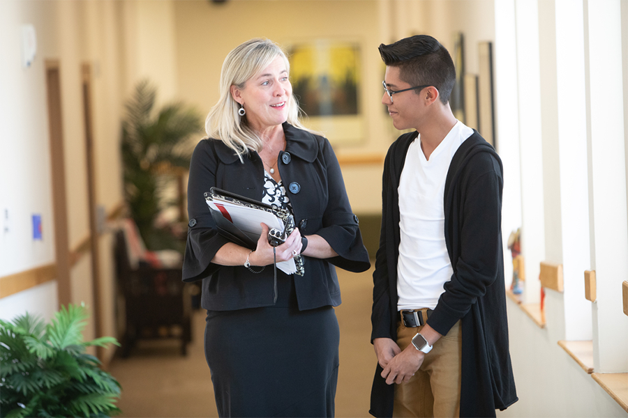 Two people standing in a hallway having a conversation.