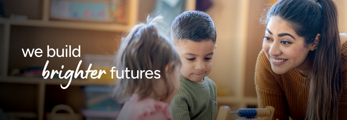 A smiling educator interacts with two young children in a warm classroom setting. The text "we build brighter futures" is prominently displayed.