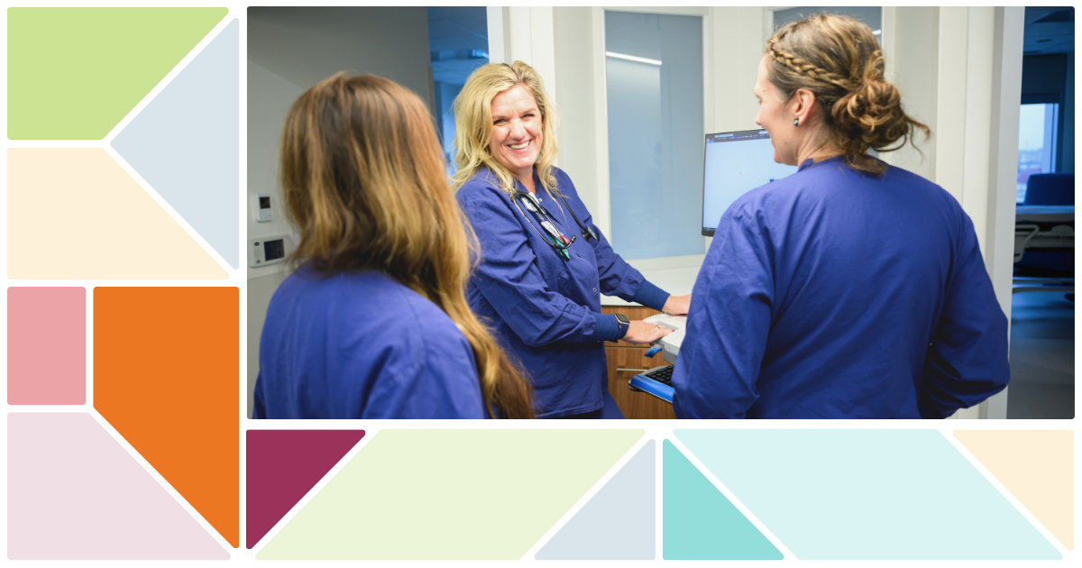Three nurses at work station in  dark blue scrubs