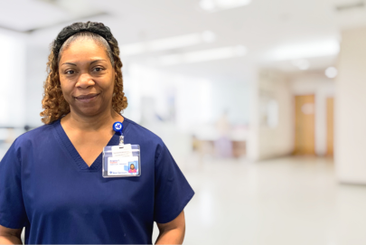 Angela F headshot in an urgent care setting wearing blue scrubs and a name badge