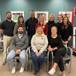 Staff team at Mercy Health Orthopedics and Sports Rehabilitation posing in a rehab facility with equipment in the background
