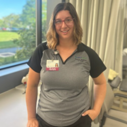 Physical therapist Jessica K. standing in a clinic space with natural light and treatment tables in the background