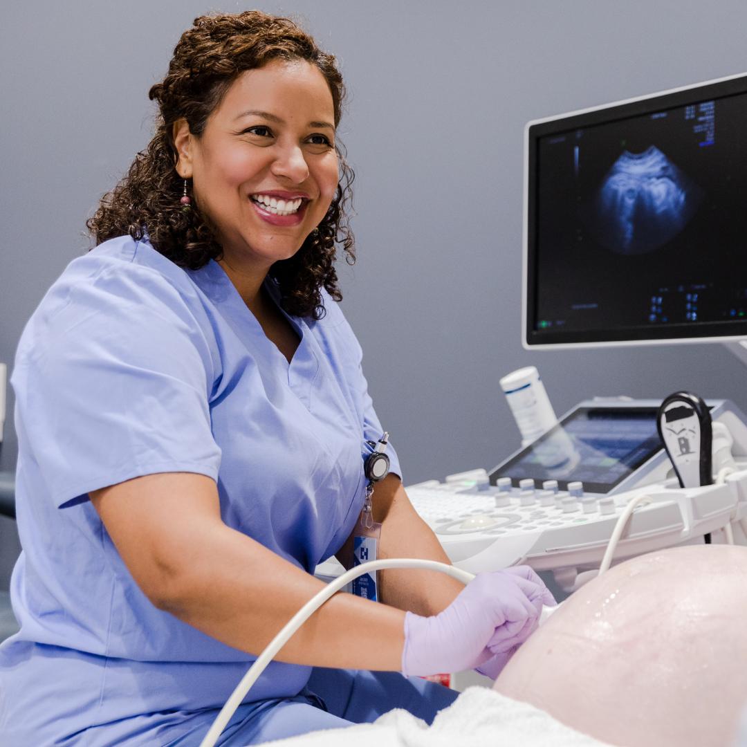 Ultrasound tech smiling while doing an ultrasound on expectant mother