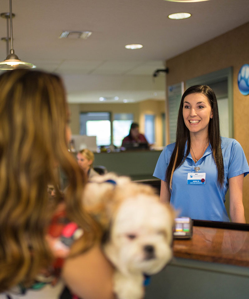 A BluePearl client care coordinator smiles while welcoming a client and their dog into care.