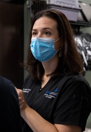 A BluePearl Client Care Coordinator talks with a client while wearing a blue facemask.