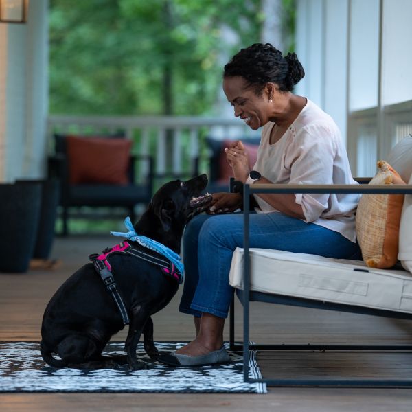 A woman and her dog sit together on a porch.