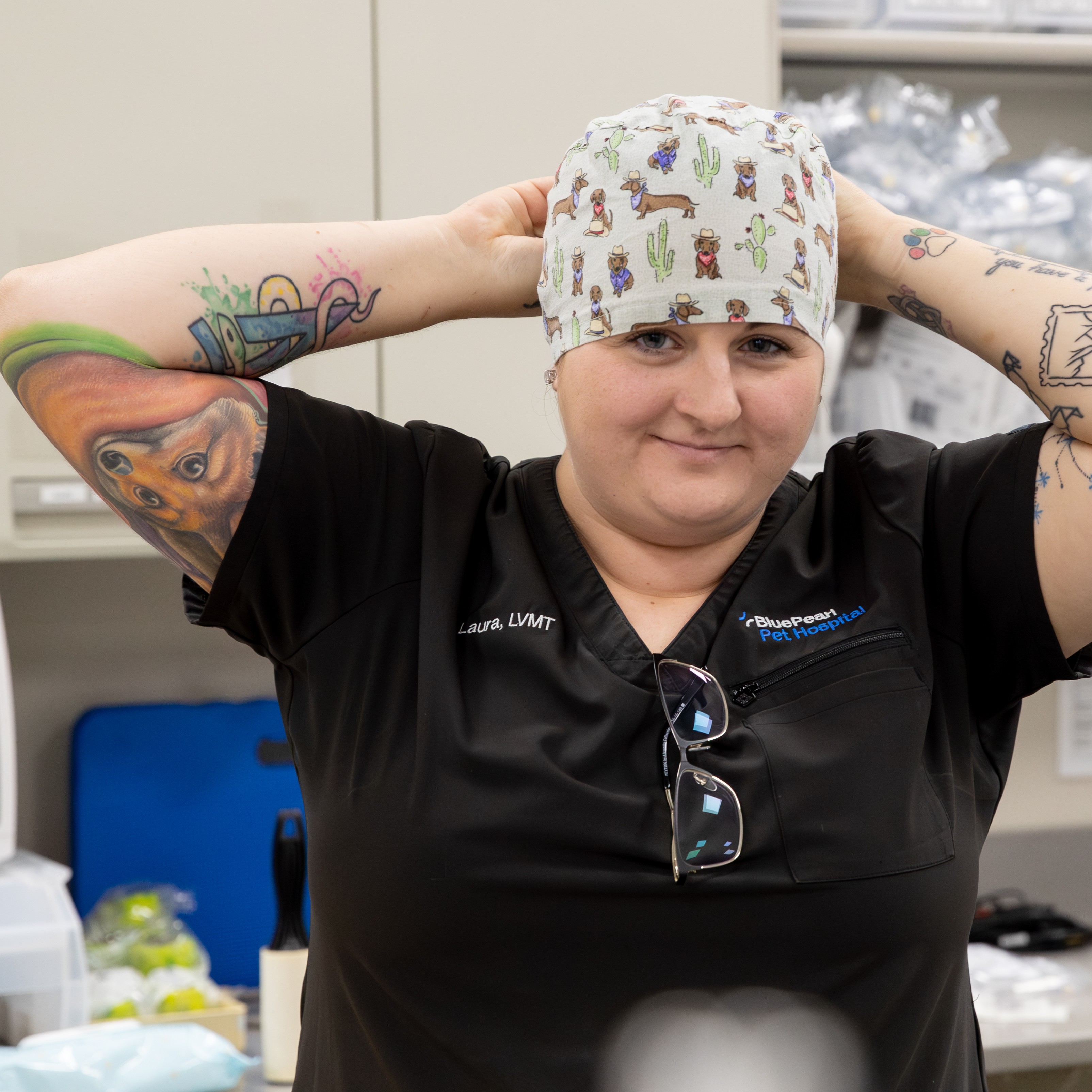 A BluePearl Associate in black scrubs ties a cap onto her head.