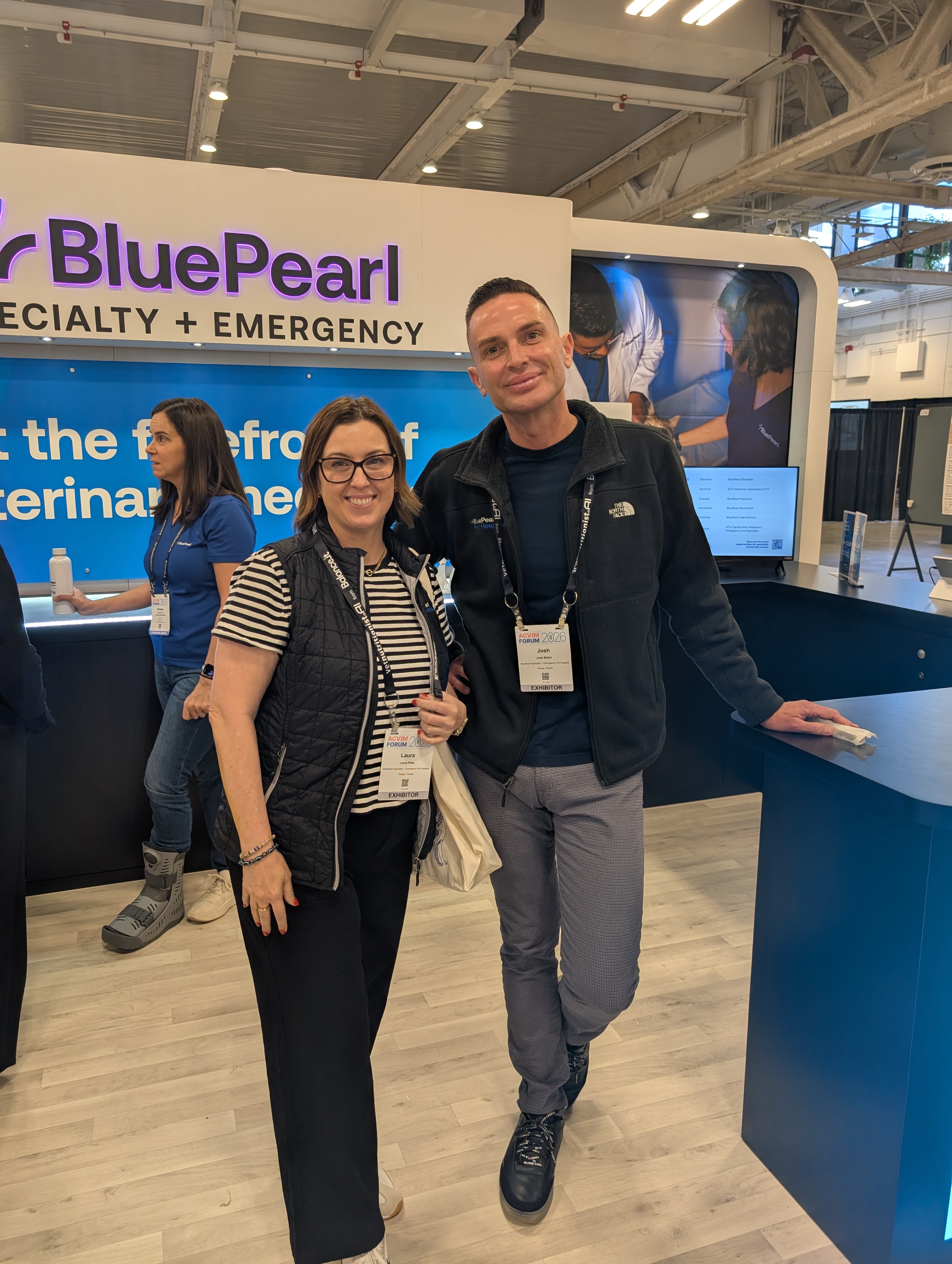 BluePearl leaders Dr. Laura Pletz and Josh Baker smile for the camera at their booth at the 2026 ACVIM Forum.
