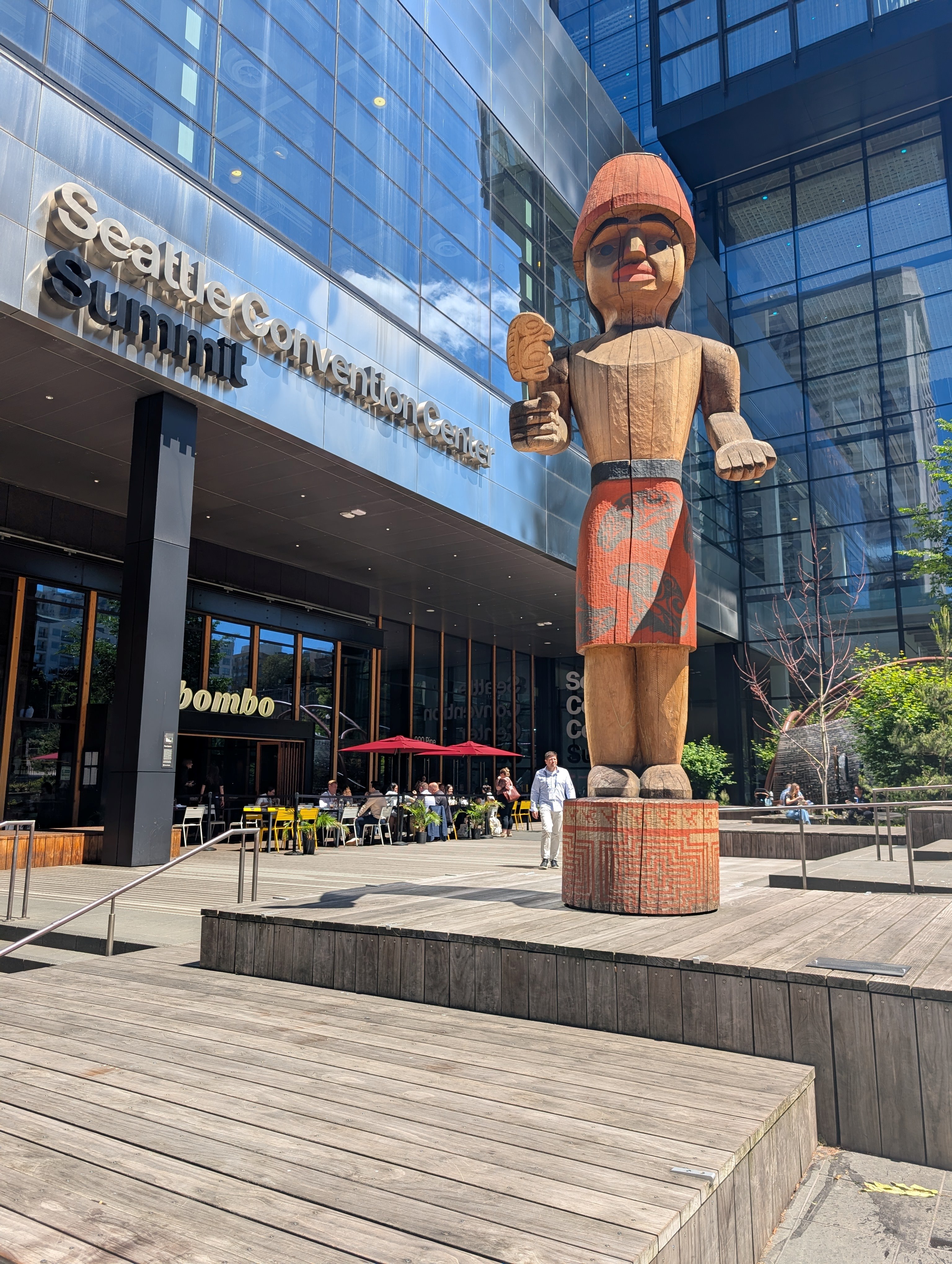 The entrance to the 2026 ACVIM Forum - the silver Seattle Summit Convention Center, with large wooden statue in front.