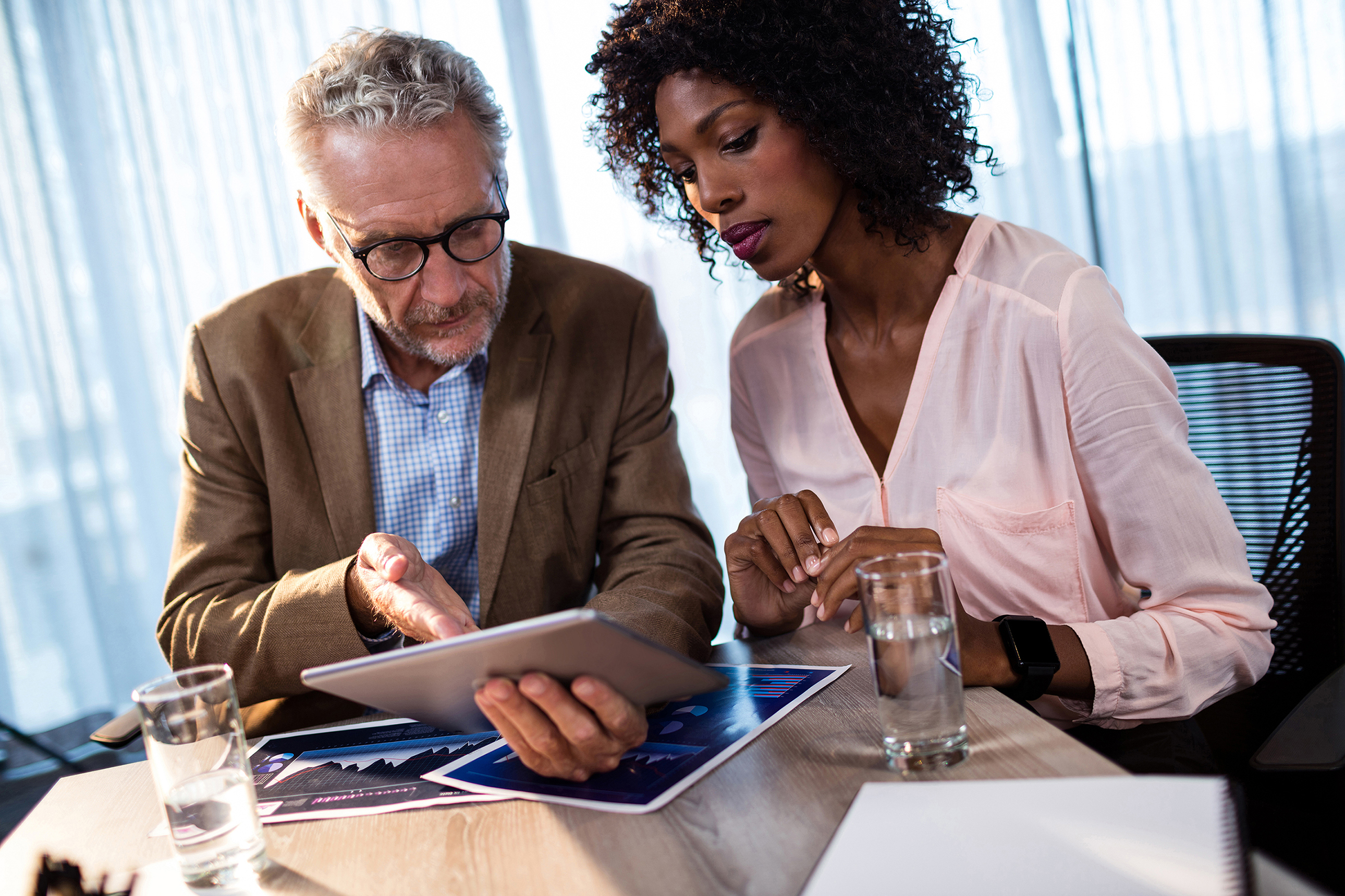 man points at tablet as woman next to him looks