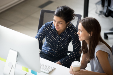 two woman on working on a computer together