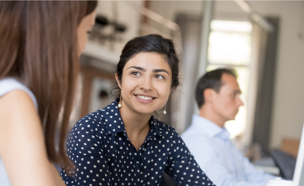 woman smiling at another woman with man in background