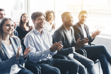 a group of interns sitting down in a row clapping