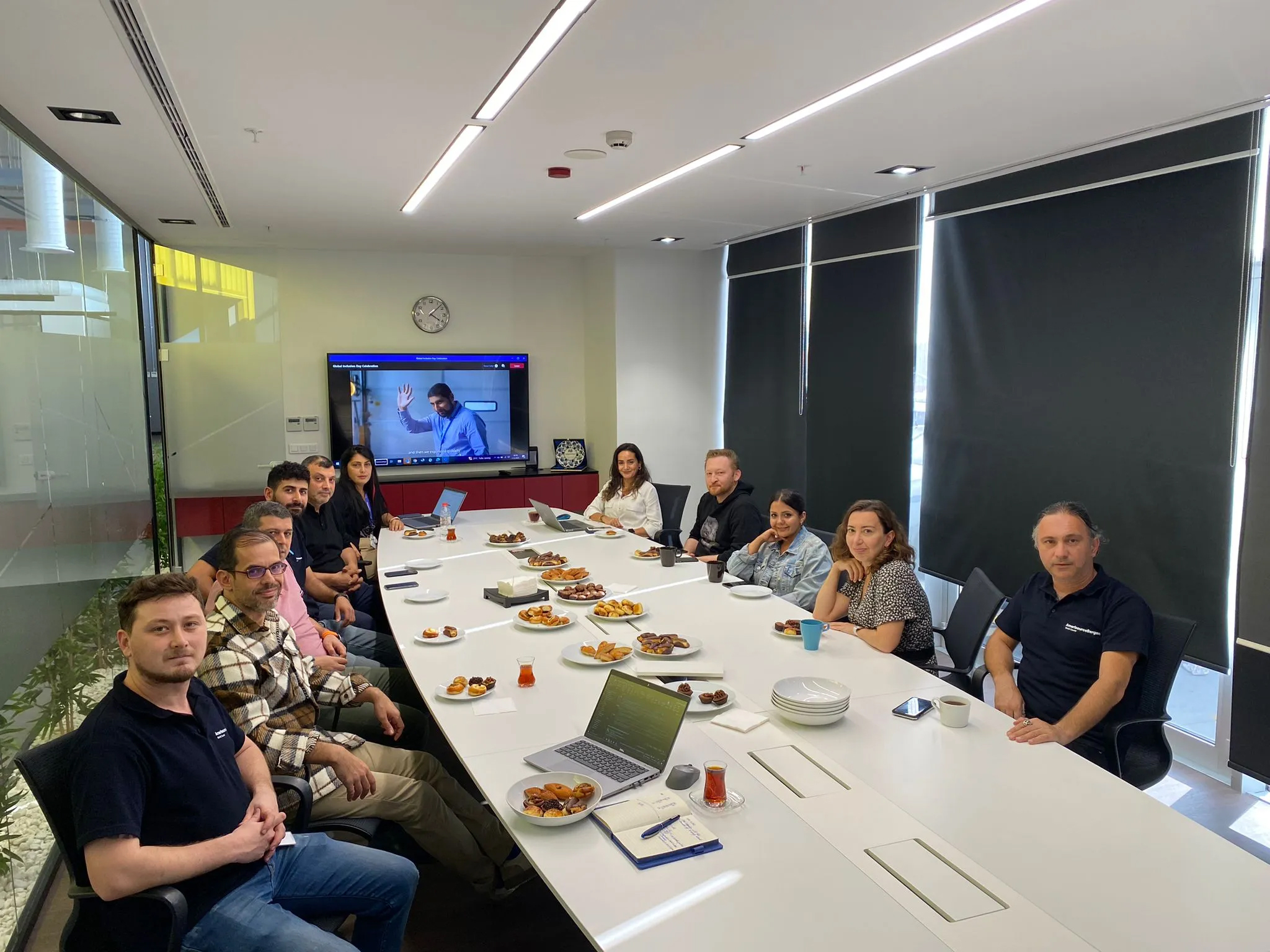 A group of Cencora team members sit together around a conference table that has food on plates.