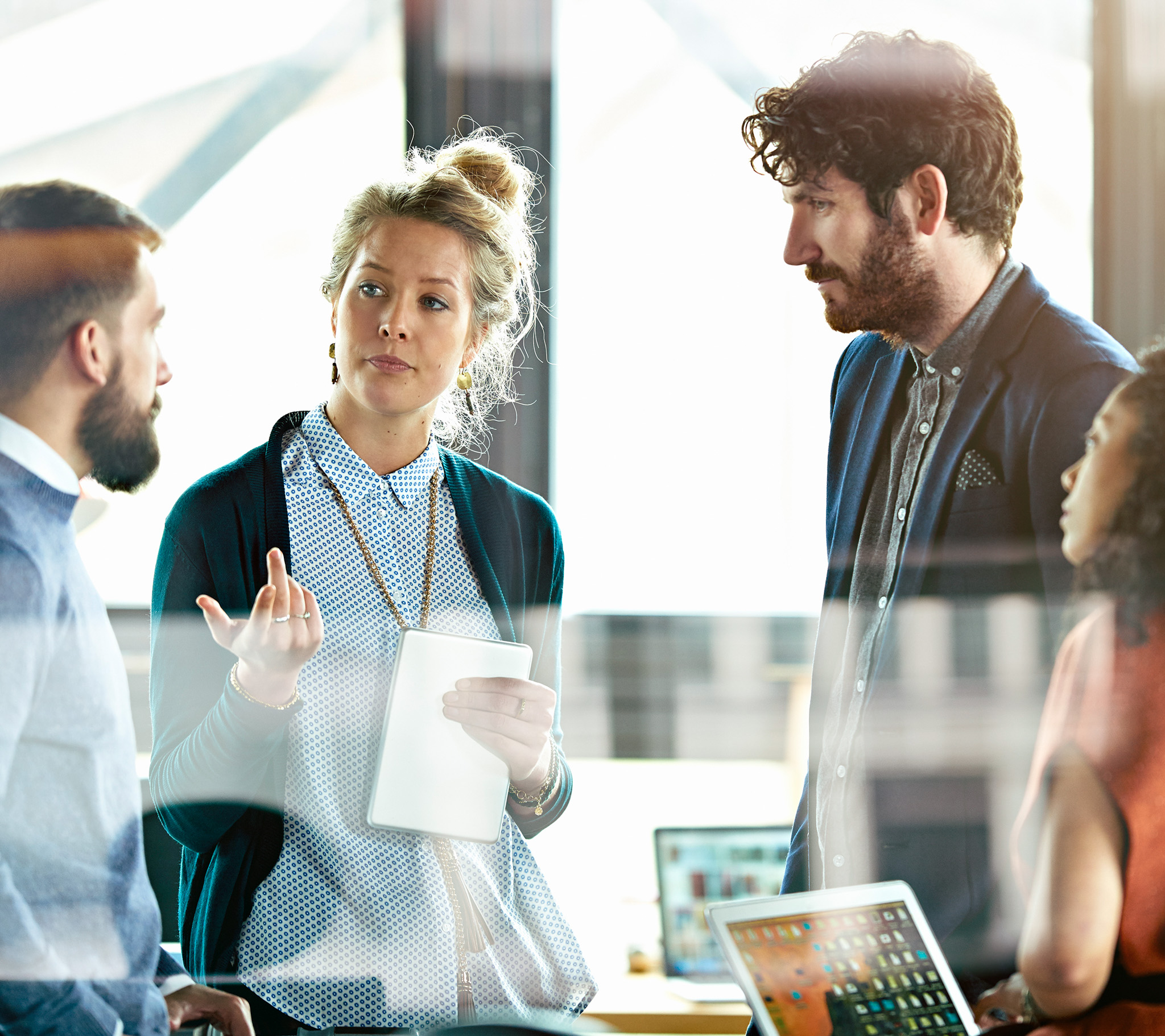 A group of young professionals converse in a modern office space.