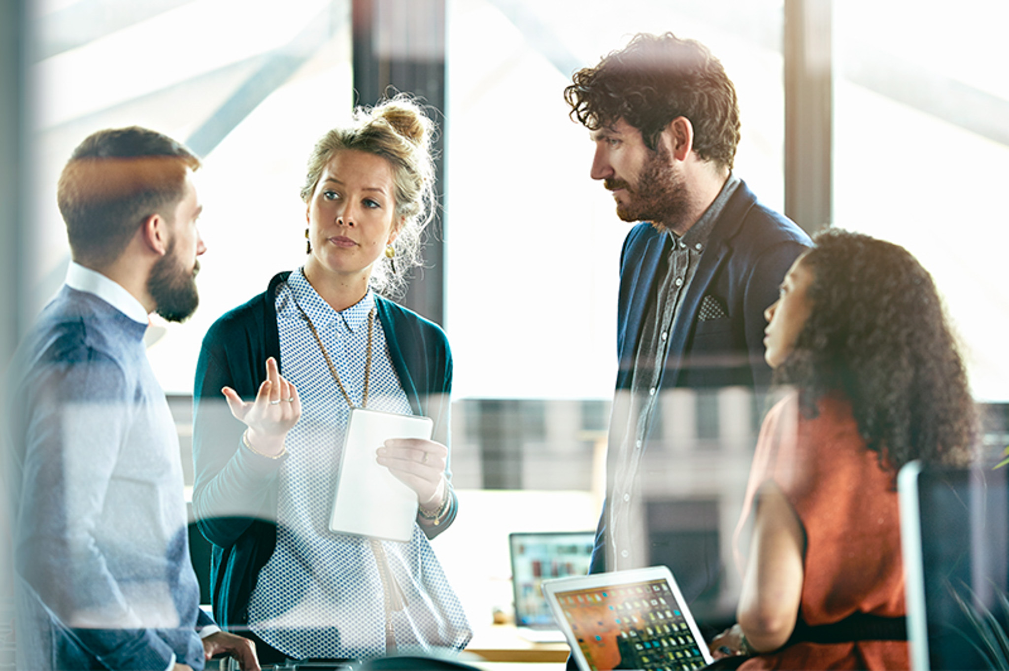 A group of young professionals converse in a modern office space.