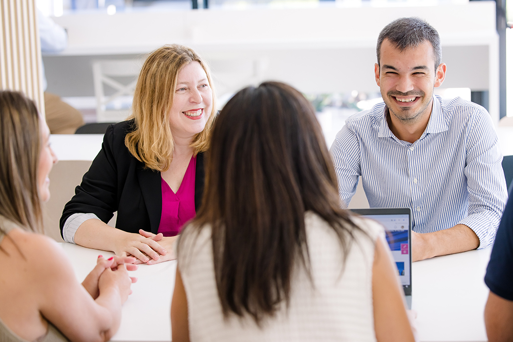 Several Cencora team members sit at a table - they are laughing and talking.