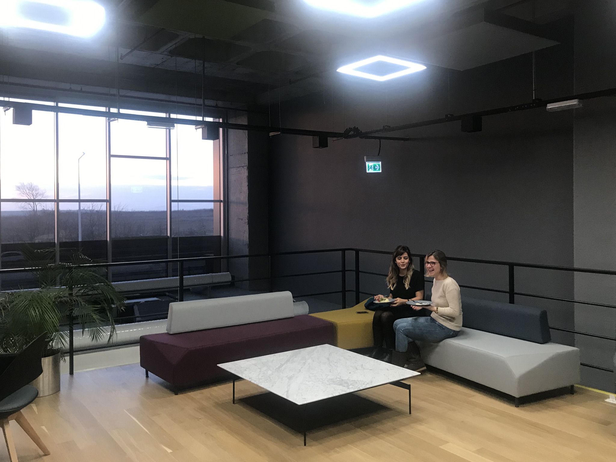 Two Cencora team members sit together on a couch in an open office area.