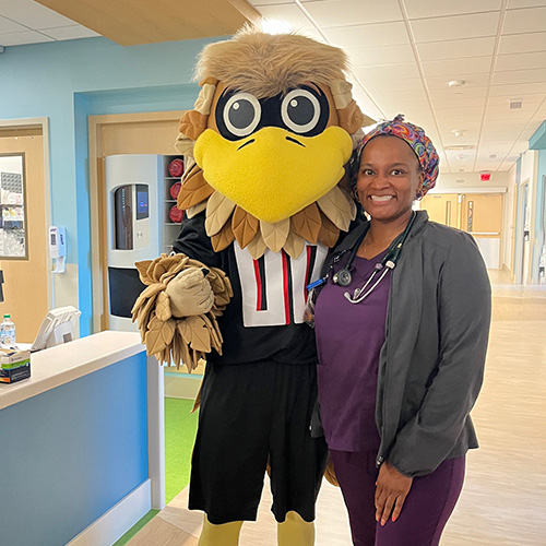 A Children’s nurse stands with Freddy Falcon during an employee engagement event at Children’s Healthcare of Atlanta. 