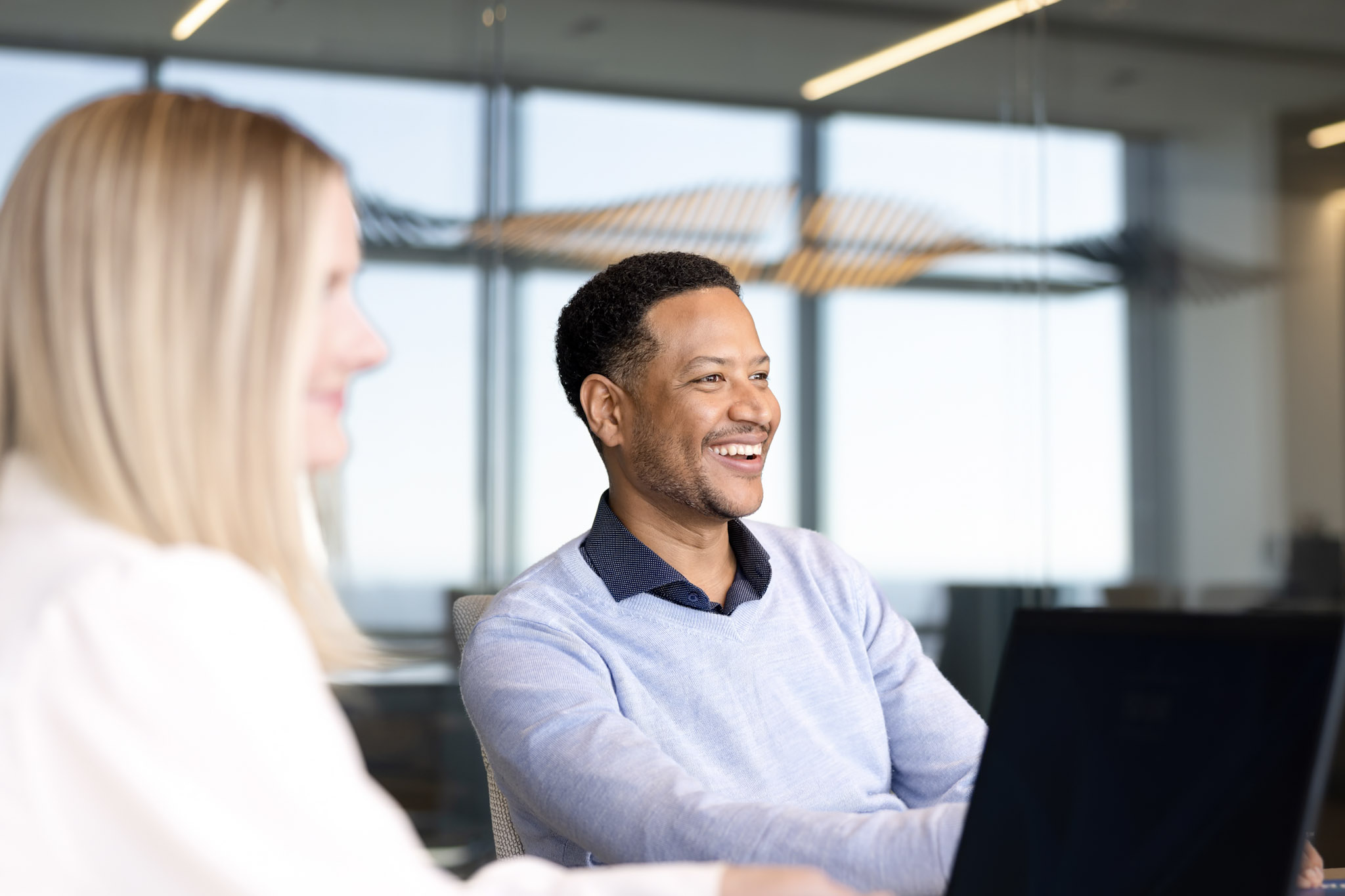 An employee smiling during a conversation with a co-worker offscreen