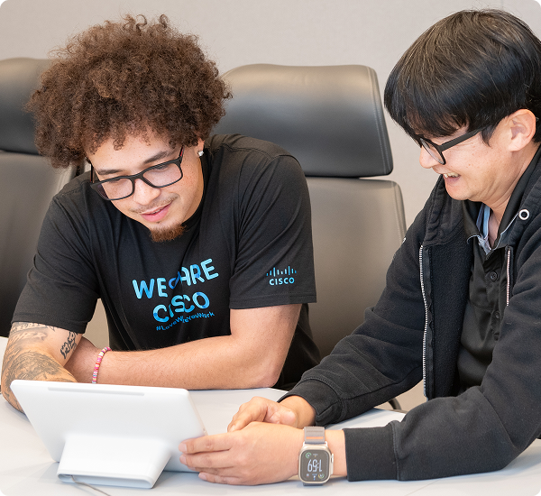 Two Cisconians collaborating on a tablet in front of them. One is wearing a "We Are Cisco" t-shirt.