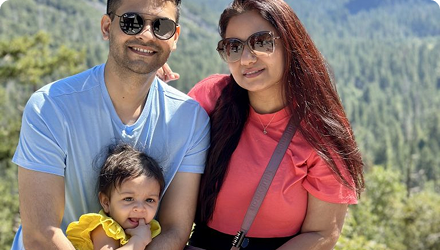 A family enjoying time together. A woman and a man sit together with a little girl in the mans arms.