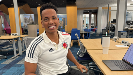 A smiling young man working at an open desk.
