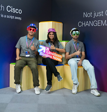 Three participants wearing photo-booth-style decorations smiling at the camera