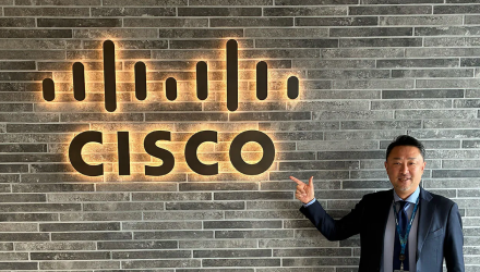 A man pointing at a sign of the Cisco logo.