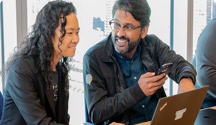 A man and a woman collaborate in front of a laptop.