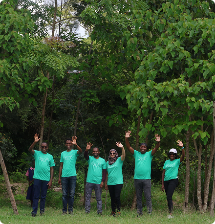 Cisco team members all wearing green t-shirts wave from a stand of trees.