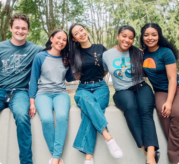 Five young Cisconians sit on a wall outside, smiling.