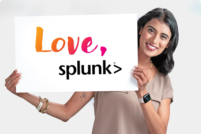 A woman smiles at the camera holding a Love, Splunk sign.