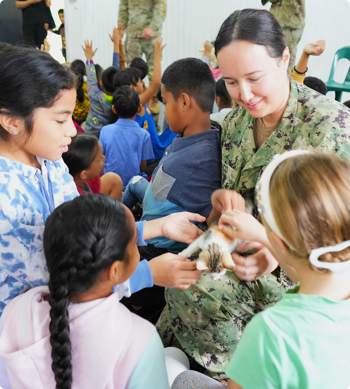 A woman in uniform works with some children.