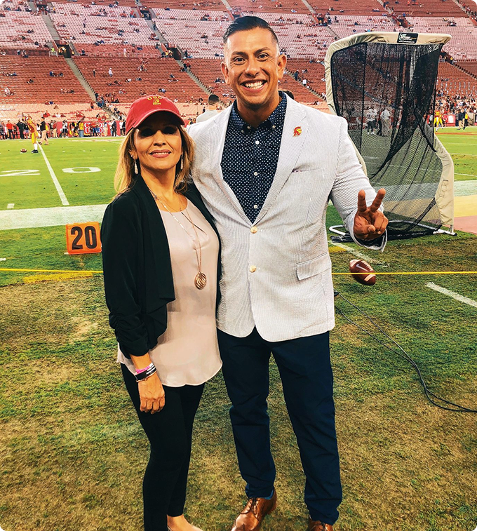  Hector Cabrera stands on an athletic field with his mother.
