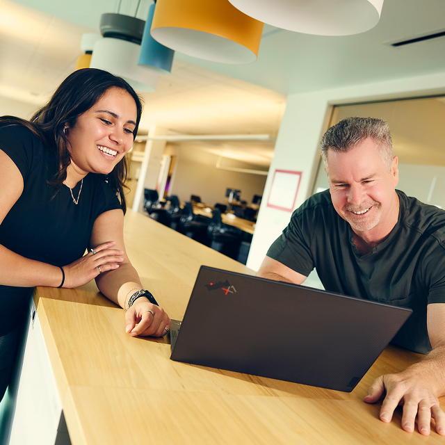 A woman and man smile at a computer in the Cisco office.