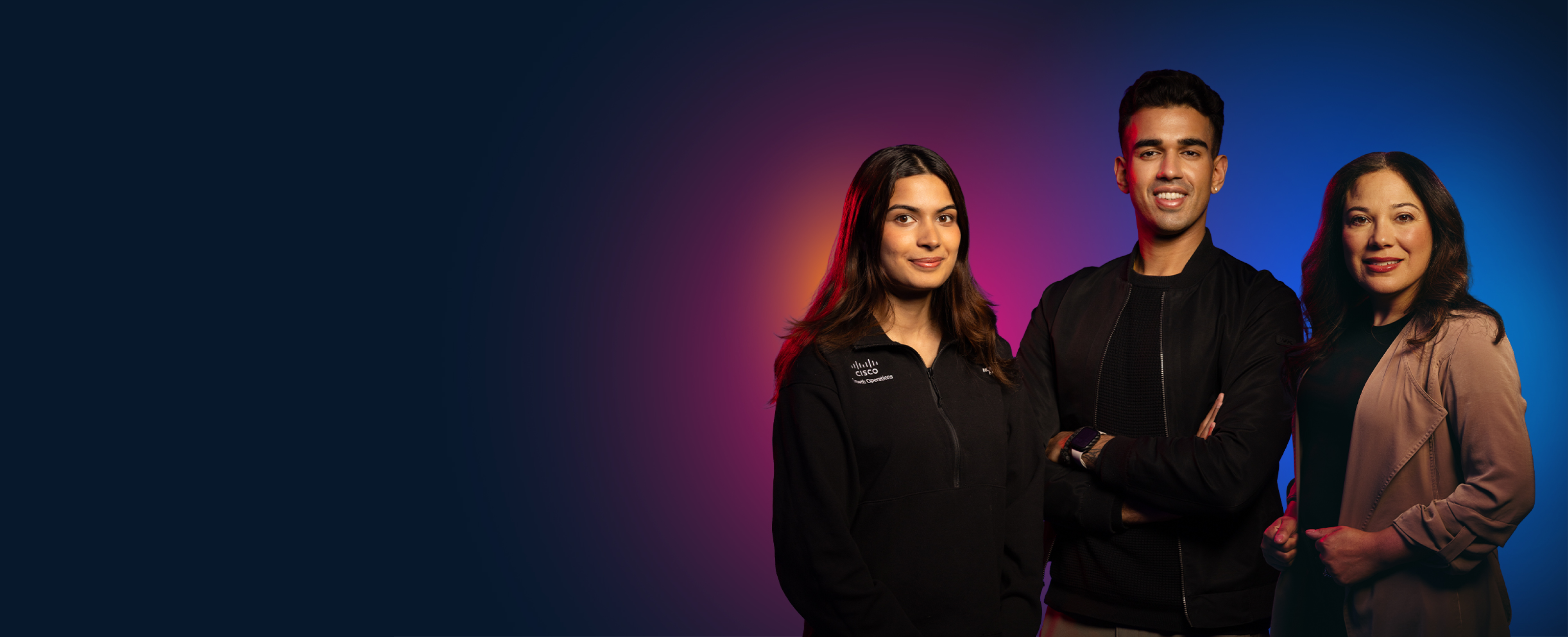 A smiling man surrounded by two women looking at the camera.