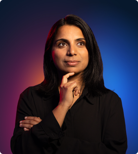 A woman wearing a black blouse holders her finger under her chin and has her other arm crossed while looking off into the distance.