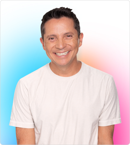 A man wearing a white t-shirt smiles brightly in front of a white background with teal, peach, and pink gradated color accents.