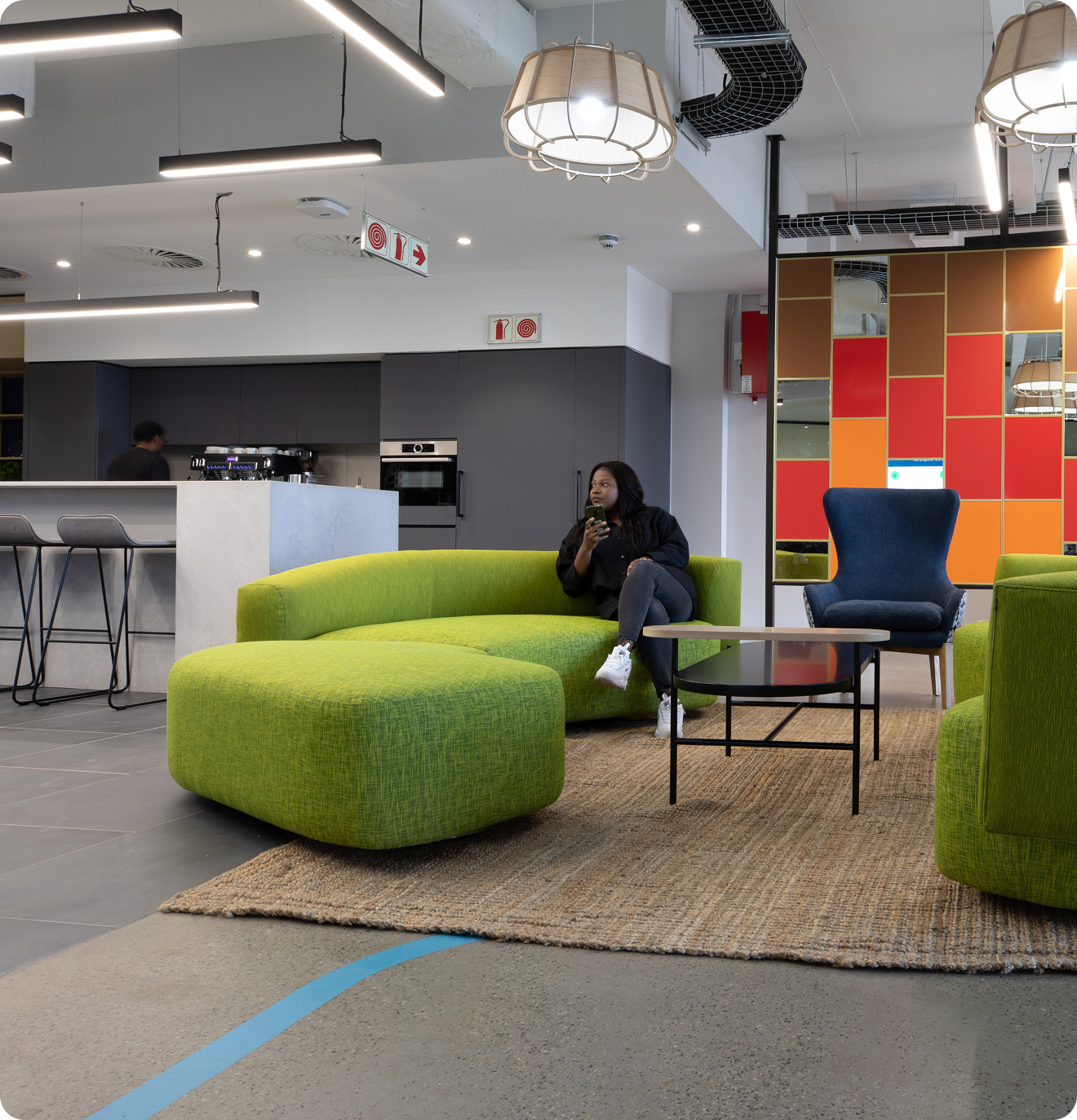 A kitchen and adjoining seating area with lime green couches and an orange and red color block wall.