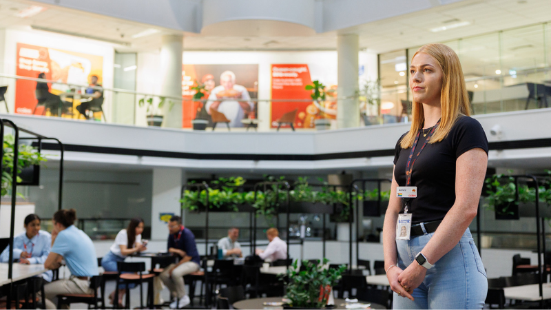 A corporate female employee standing in the Coles SSC staring into the distance
