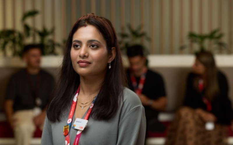 A female Coles graduate standing in the Coles Store Support Centre with a group of fellow graduates behind her